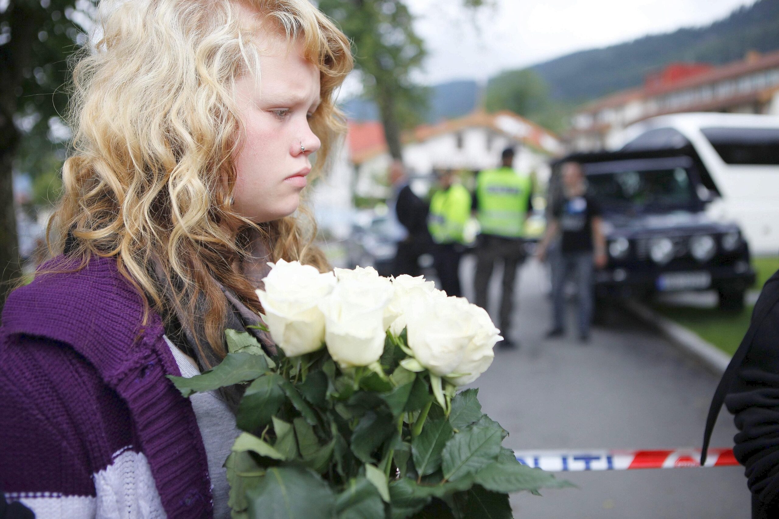 Ein Mädchen legt weiße Rosen nieder.