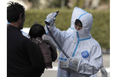 Das war an Tag zwei nach dem Beben: Die Sorge vor einer Atomkratastrophe wächst. In Koriyama werden dieser Mann und sein Kind auf Strahlung untersucht.