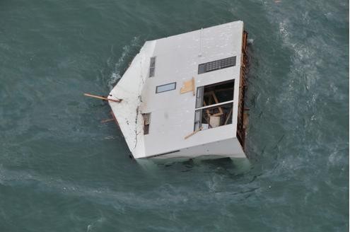 Ein im Meer treibendes Haus, fotografiert von ein Hubschrauber der US Air Force aus.