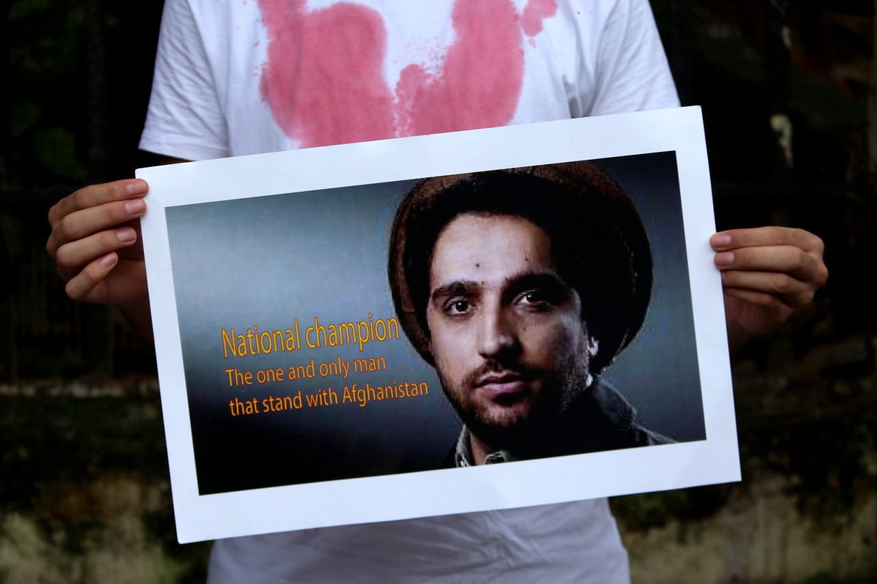 Ein Junge hält ein Bild von Ahmad Shah Massoud in den Händen.