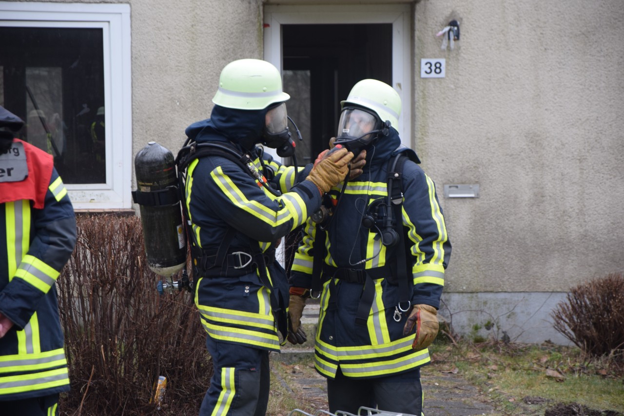 Die Männer helfen sich beim Abmontieren der Atemschutzmaske.