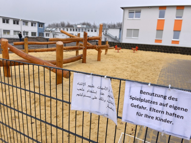 Mehrsprachige Hinweise hängen am Zaun der Kita.