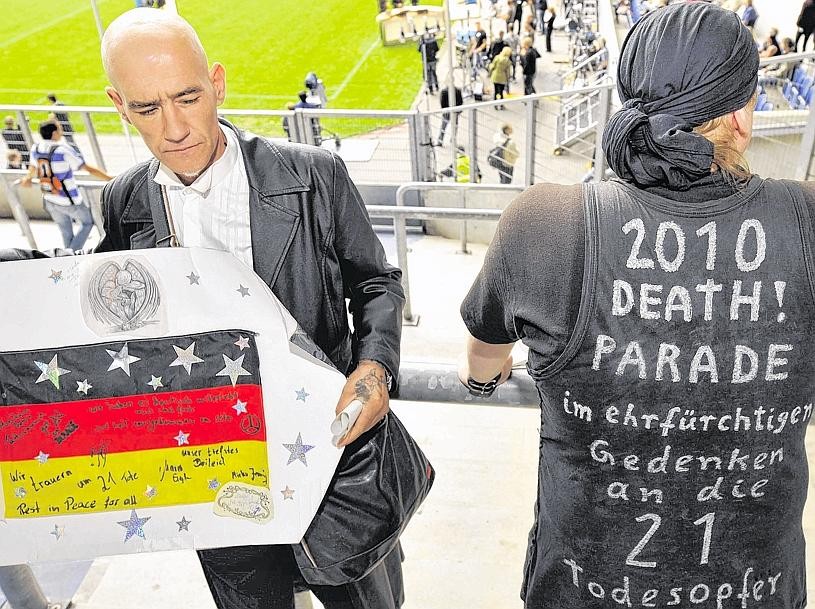 Auf Wunsch der Hinterbliebenen hat die NRW-Staatskanzlei von Ministerpräsidentin Kraft die Organisation der Gedenkfeier übernommen (im Bild: die Trauerfeier im MSV-Stadion 2010). Am 18. Juli gibt sie Details bekannt. Von den Angehörigen wurde auch der Wunsch an sie herangetragen, dass Adolf Sauerland und Rainer Schaller nicht teilnehmen sollen. In einem Medienbericht erklärt Schaller, er komme aus Respekt vor den Angehörigen nicht. Er gesteht ein, er habe „Angst vor dem Tag“. „Ohne die Veranstaltung wären die Menschen nicht gestorben“, sagt Schaller in einer VOX-Doku