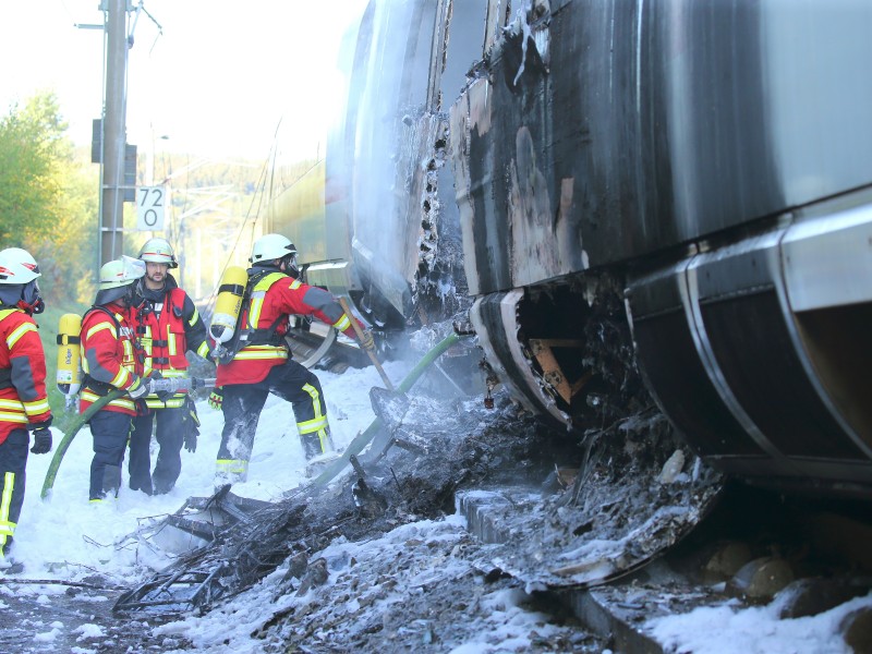 Feuerwehrleute  sind mit Nachlöscharbeiten beschäftigt.