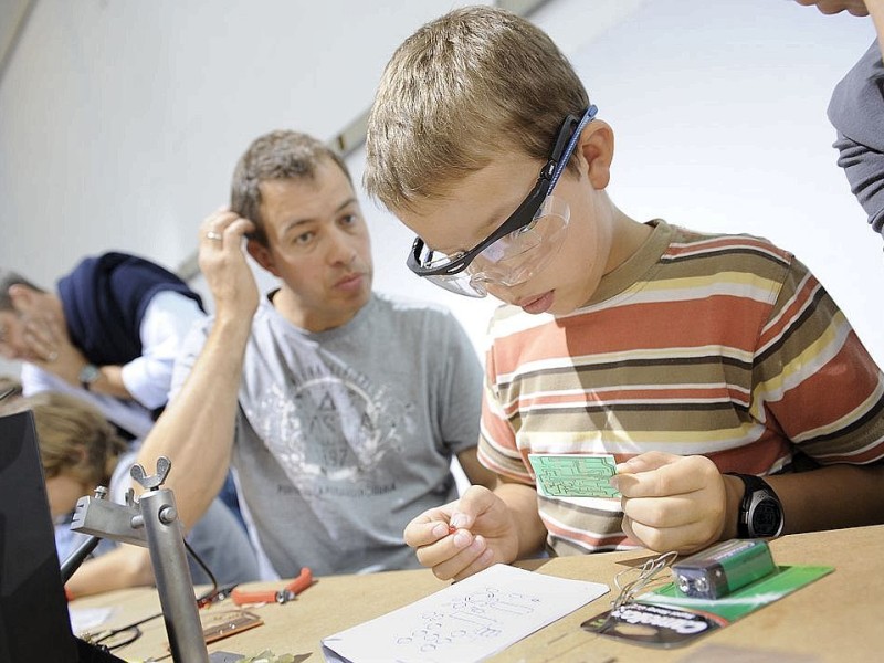 Der Vater kratzt sich schon am Kopf, während der Filius noch über dem Schaltplan brütet. Szene während eines Löt-Workshops. Foto: Matthias Graben / WAZ FotoPool