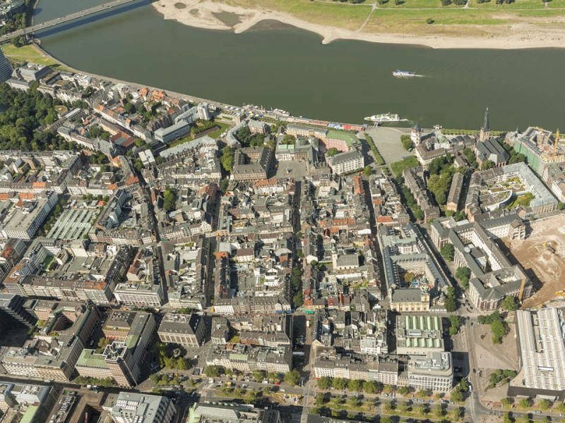 Die Rheinpromenade und die Altstadt zwischen Landtag (links) und St. Lambertus (rechts). Rechts neben dem Wahrezeichen der Alstadt entstehen im ehemaligen Theresienhospital (Kameha Residence).