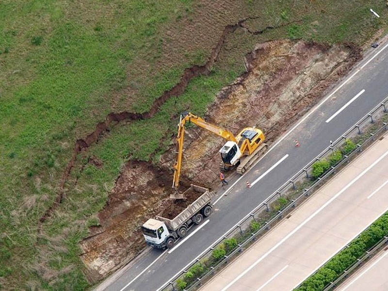 Ein Bagger trägt am Erfurter Kreuz bei Molsdorf in Thüringen die rund 2000 Kubikmeter Erde ab, die der Regen der vergangenen Tage hat abrutschen lassen.