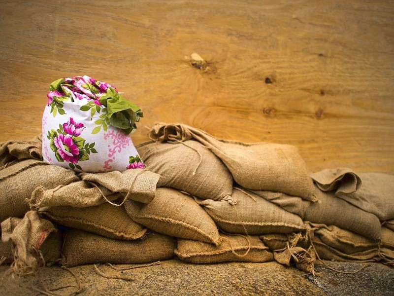 Dem Anschein nach ein Handmade gefertigter Sandsack steht auf normalen Sandsäcken vor einer Türe in Dresden (Sachsen).