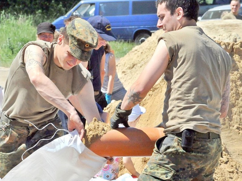Bundeswehrsoldaten befüllen direkt an der Elbe in Bälow (Brandenburg) Sandsäcke.
