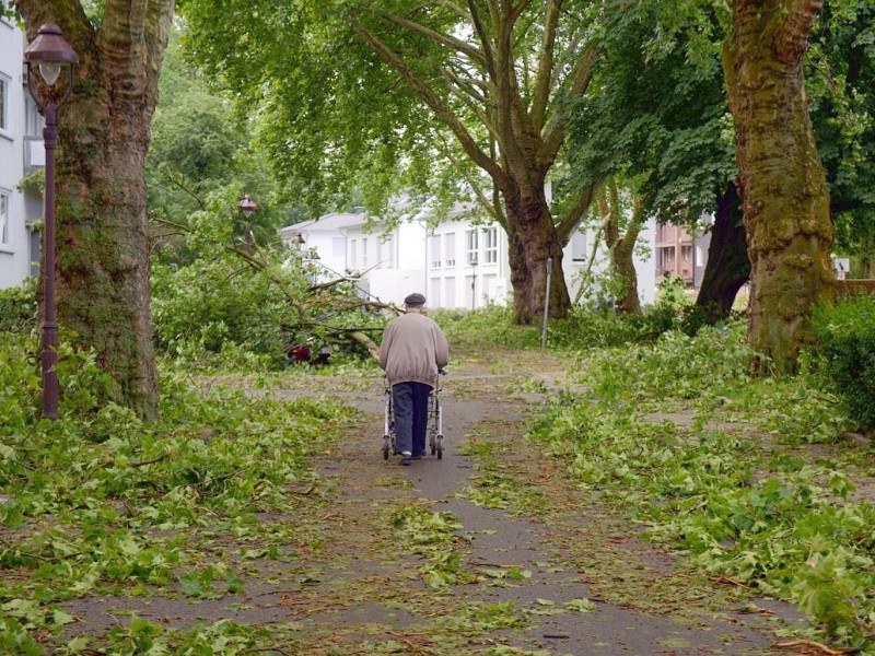 Ein Mann geht mit seinem Rollator in Gelsenkirchen nach dem Unwetter über eine Straße.