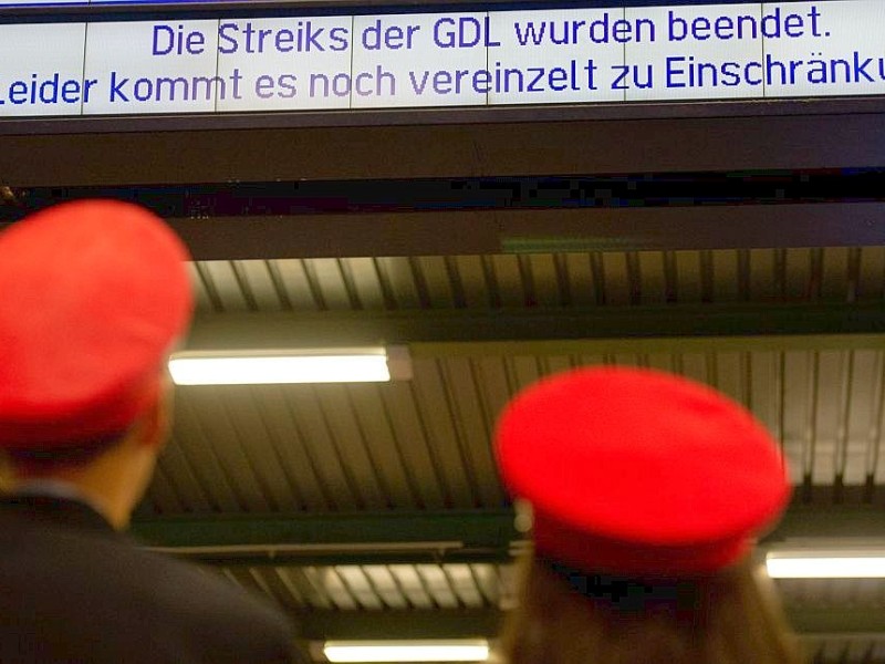 Zwei Mitarbeiter der Deutschen Bahn stehen in Stuttgart am Hauptbahnhof vor einer Anzeigetafel mit der Aufschrift Die Streiks der GDL wurden beendet. Leider kommt es noch vereinzelt zu Einschränkungen.