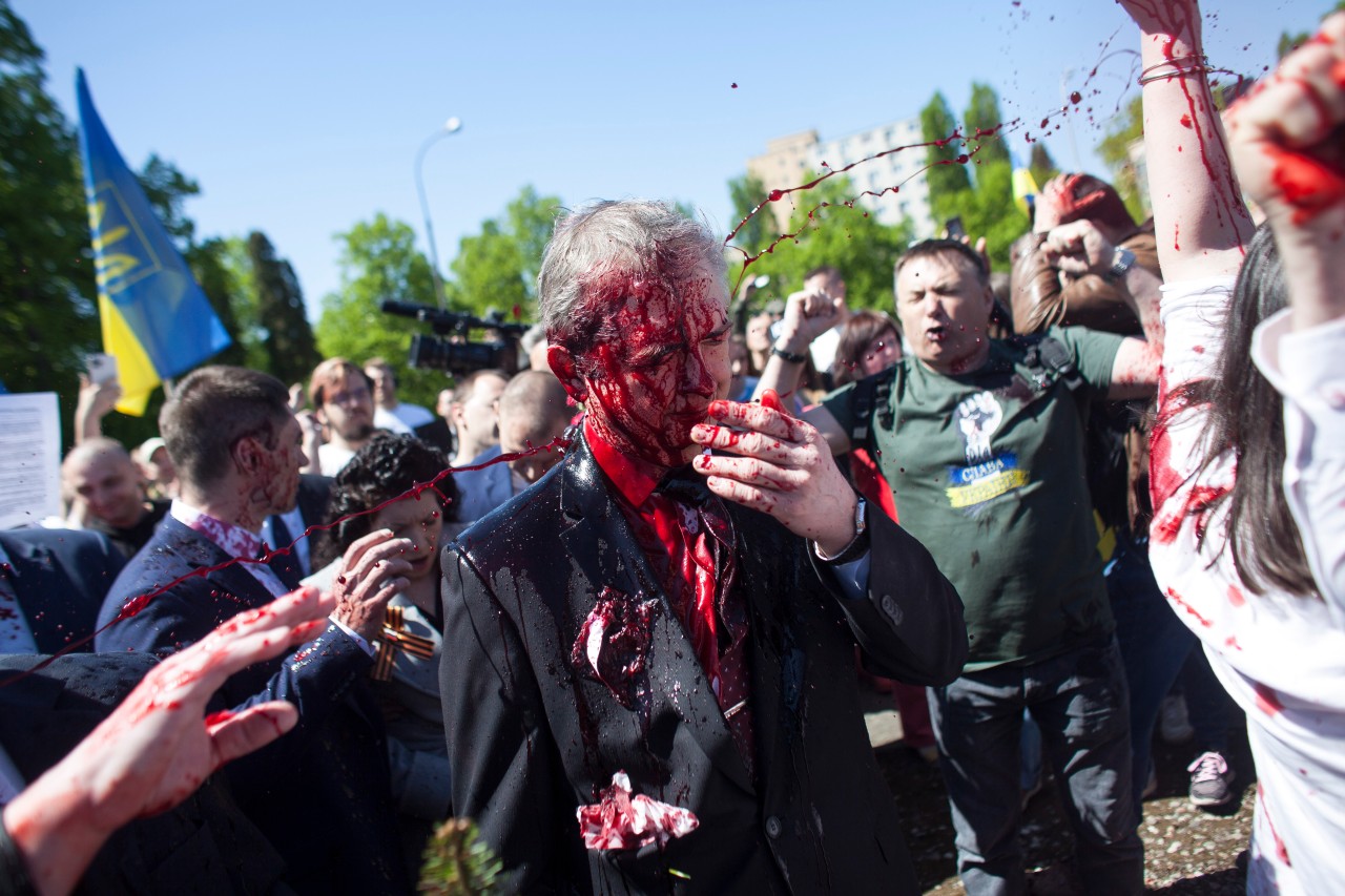 Sergej Andrejew (M), russischer Botschafter in Polen, wird bei einer Kranzniederlegung auf dem Friedhof für die gefallenen sowjetischen Soldaten im Zweiten Weltkrieg in Warschau am Montag, 9. Mai 2022, von Demonstranten mit roter Farbe bespritzt. 