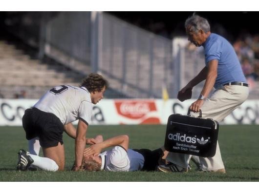 Bernd Schuster (Mitte) liegt verletzt am Boden, Masseur Erich Deuser (re.) eilt hinzu, daneben Bernd Dietz. Foto: imago