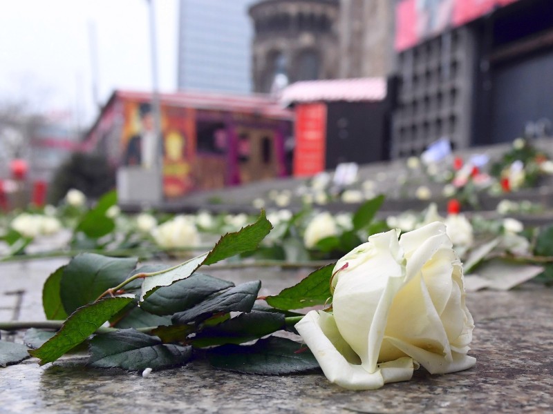 Als Zeichen der Trauer säumen weiße Rosen den Riss im Boden.