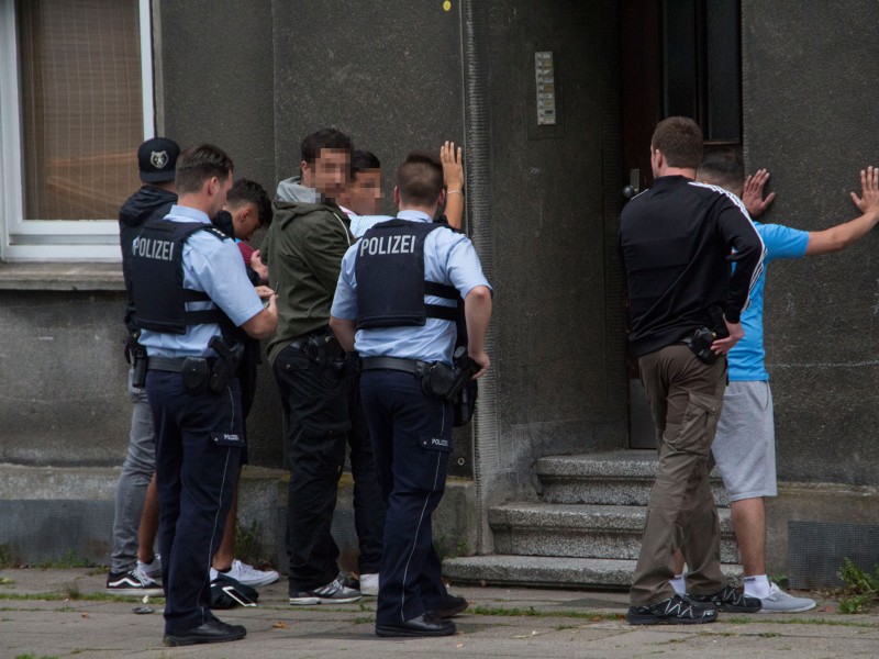 Die Polizei durchsucht die Männer, die aus dem Fenster geschossen haben.