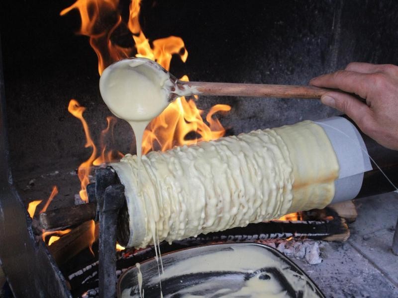 Da ist eine ruhige Hand gefragt: Der Teig muss beim Backen der Prügeltorte über dem offenen Feuer dosiert aufgetragen werden.