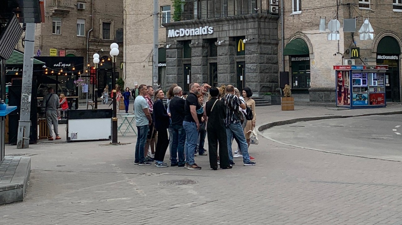 Eine Touristengruppe steht auf dem Maidan vor einer Filiale von McDonald's.