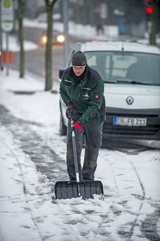 Ein Mann räumt in Bochum den Gehweg der Friederikastraße.