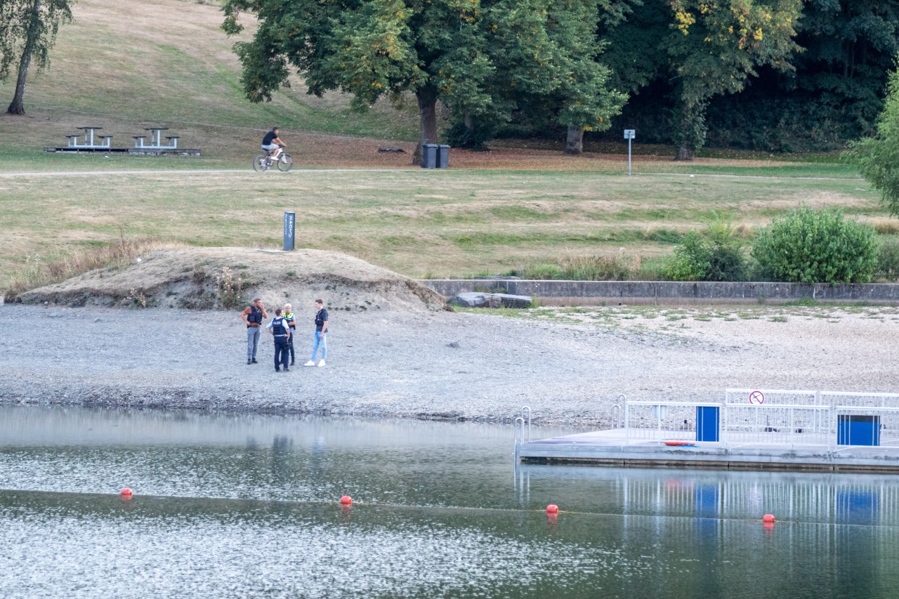 Polizisten stehen am Ufer eines Badesees. In dem Gewässer hatten zwei Kinder am Donnerstag (25. August) einen Badeunfall. 