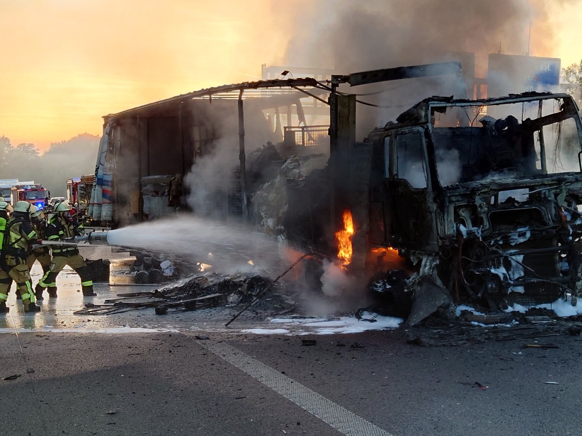 Auf der A1 brennt ein LKW lichterloh. Feuerwehrmänner versuchen die Flammen zu löschen.