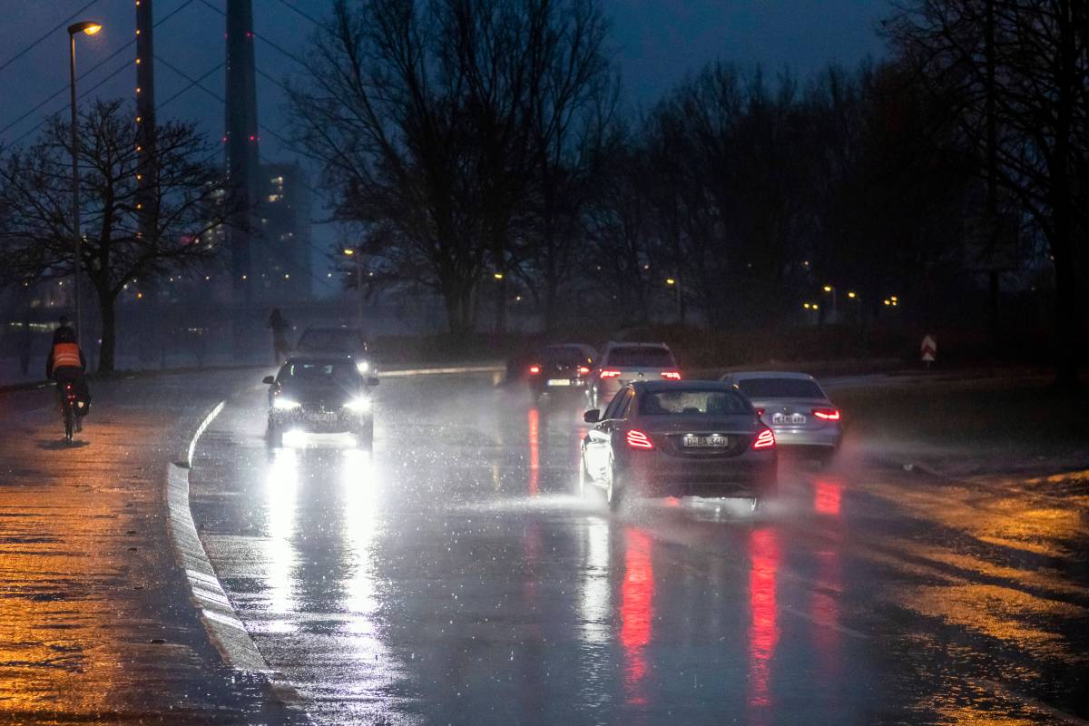 In Düsseldorf fahren Autos über eine regennasse Straße.