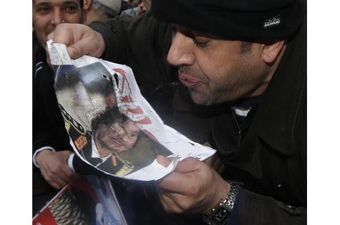 Man muss kein arabisch sprechen, um dieses Bild zu verstehen: Ein Mann spuckt auf ein Foto von Gaddafi. 