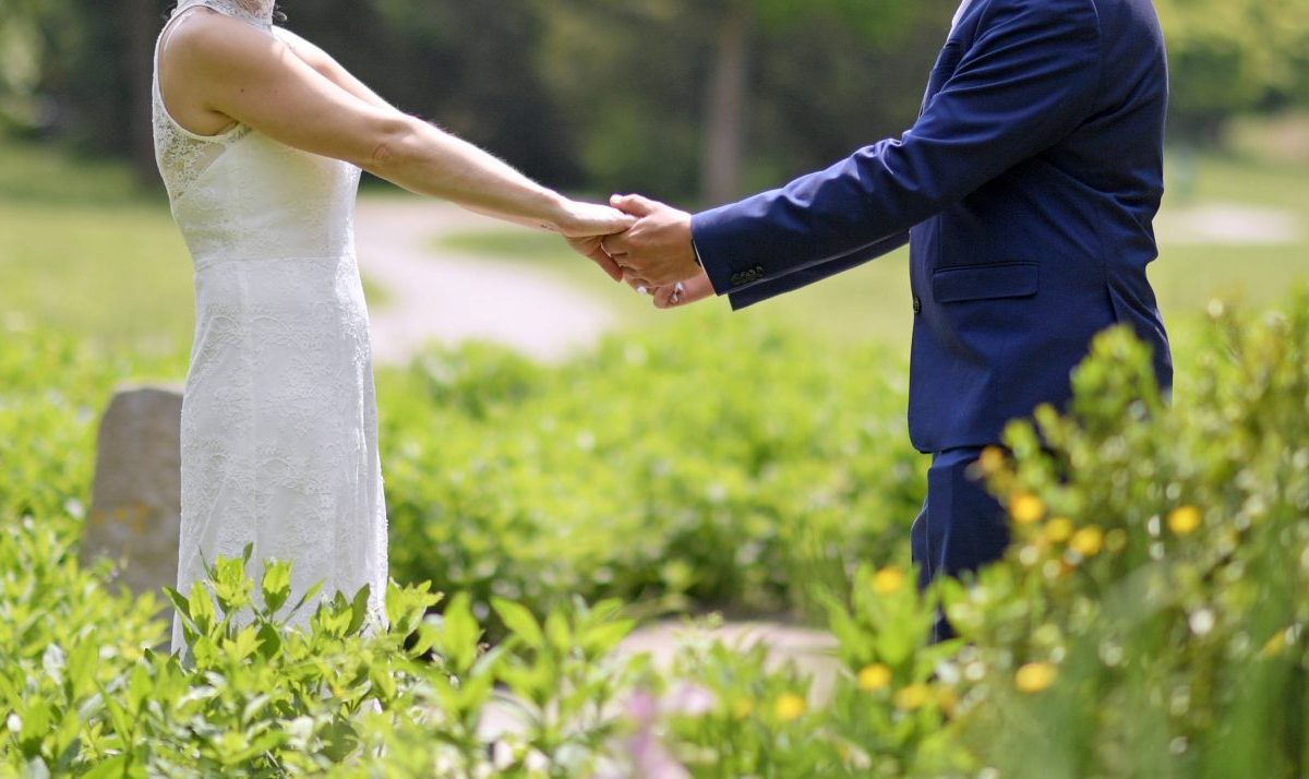 Hochzeit Brautpaar Hand in Hand auf Wiese