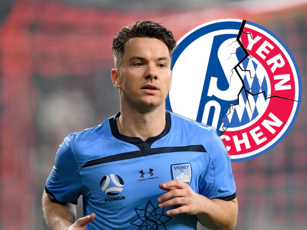 Alexander Baumjohann schaut auf die Wappen von Schalke und Bayern.