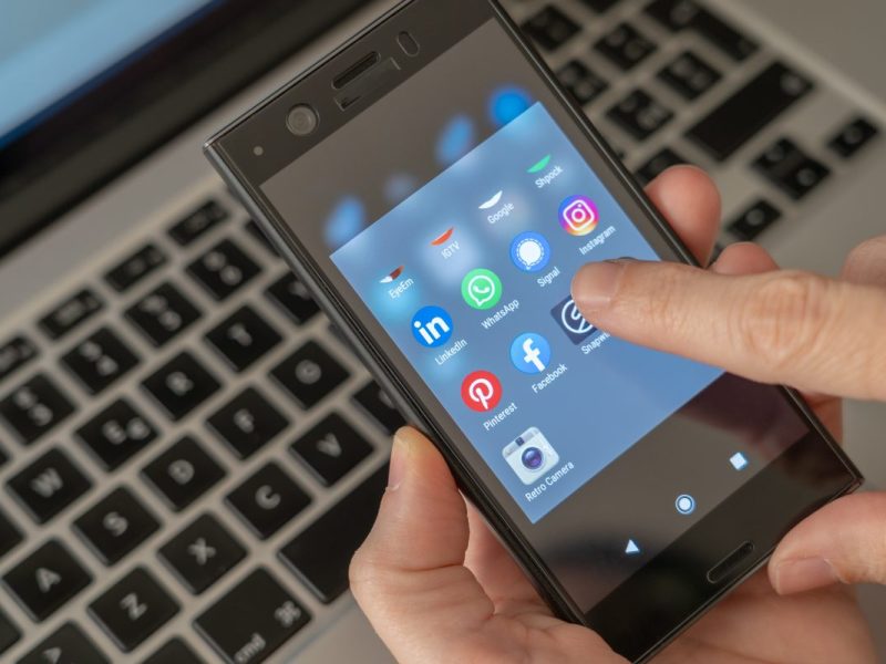 Whatsapp App auf Handy mit Laptop im Hintergrund