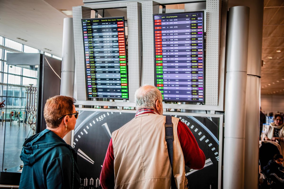 Urlaub in den Osterferien Paar sieht sich Abflugtafel im Flughafen an