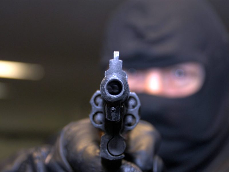 Maskierter Mann richtet Pistole auf dich