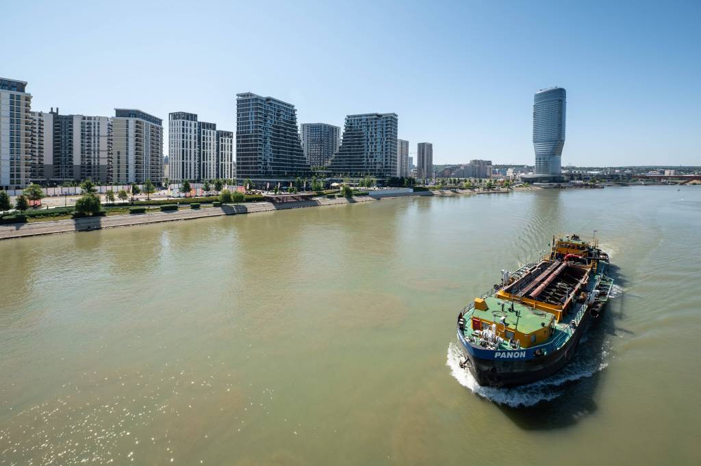 Ein Schiff fährt auf der Save am Waterfront an Hochhäusern und dem Belgrade Tower vorbei. Belgrad Serbien