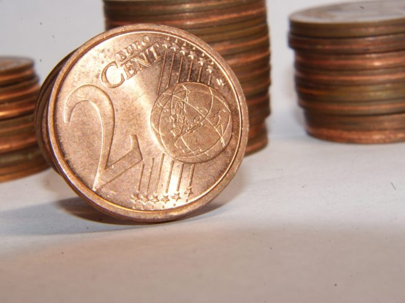 Nahaufnahme einer 2-Cent-Münze vor einem Stapel mit Cent-Münzen.