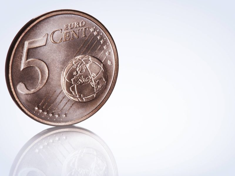 Eine 5-Cent-Münze steht senkrecht auf dem Boden.