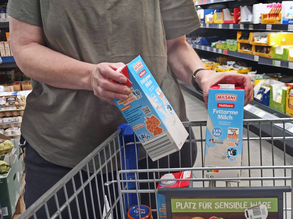 Eine Frau packt Milchtüten in den Einkaufswagen.