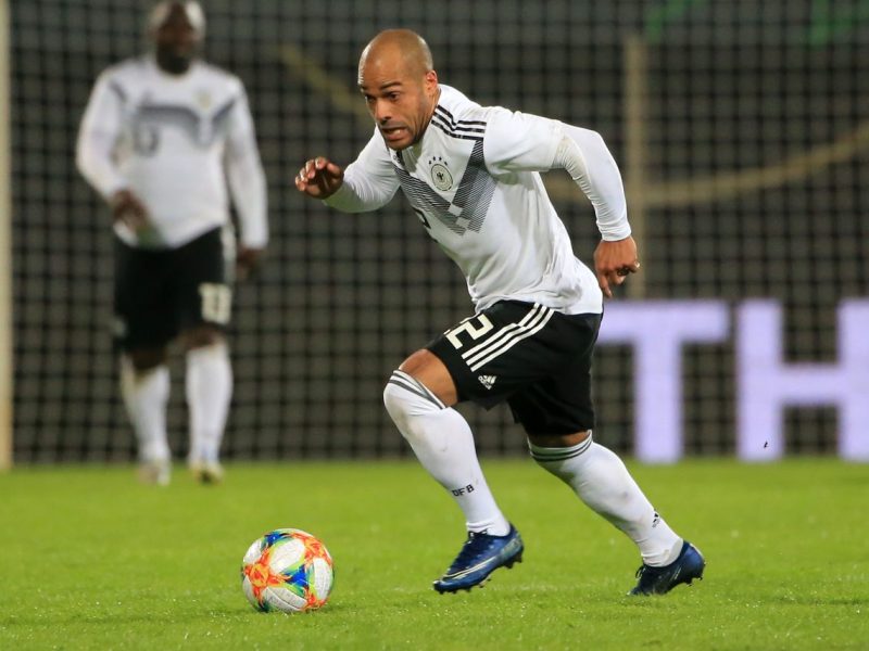 Auf dem Bild ist David Odonkor zu sehen. Er ist auf einem Fußballplatz. Er rennt einem Ball hinterher und trägt ein weißes Deutschland Trikot mit schwarzer Hose.