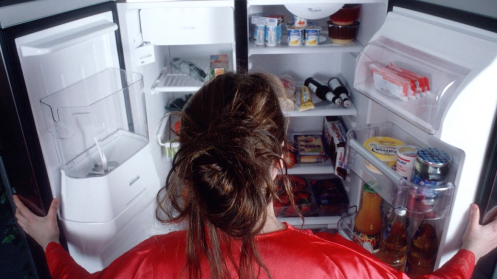 Eine Frau vor dem offenen Kühlschrank.