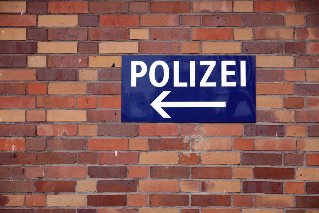 Auf einer Mauer hängt ein Wegweiser zur nächsten Polizeiwache.