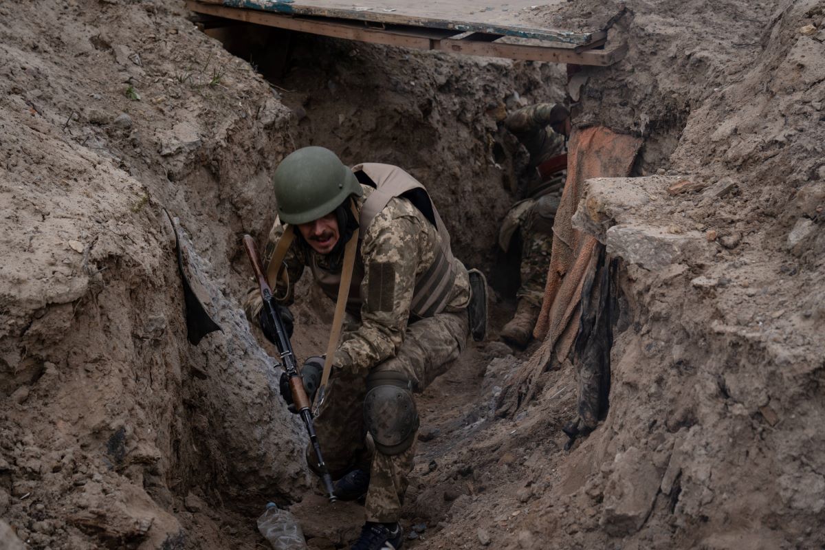 Ein Soldat hockt mit Gewehr im SchÃ¼tzengraben.
