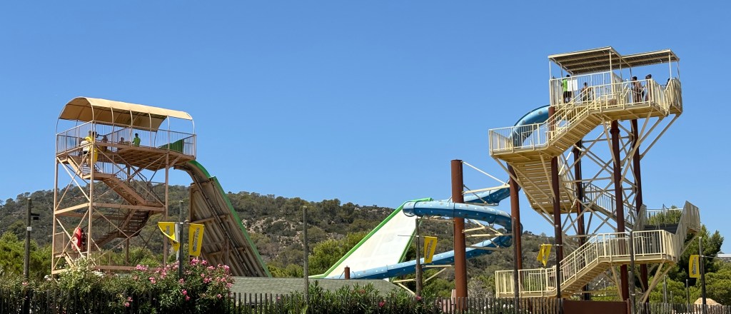 Blick auf eine Halfpiperutsche und eine blaue Spiralrutsche aus dem Western Water Park in Magaluf auf Mallorca.