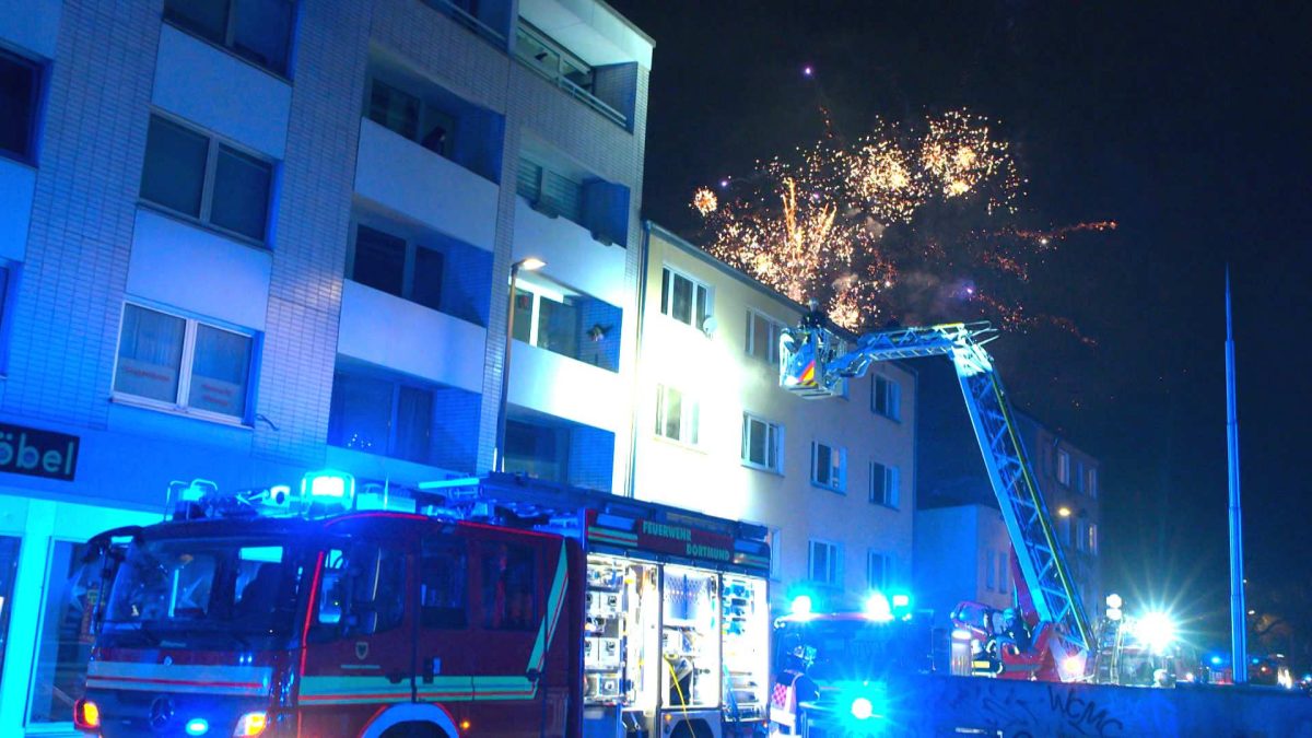 In Dortmund lÃ¶schte die Feuerwehr einen Wohnungsbrand, ausgelÃ¶st durch eine Silvester-Rakete. WÃ¤hrenddessen erfÃ¼llt Feuerwerk den Himmel Ã¼ber der Stadt.